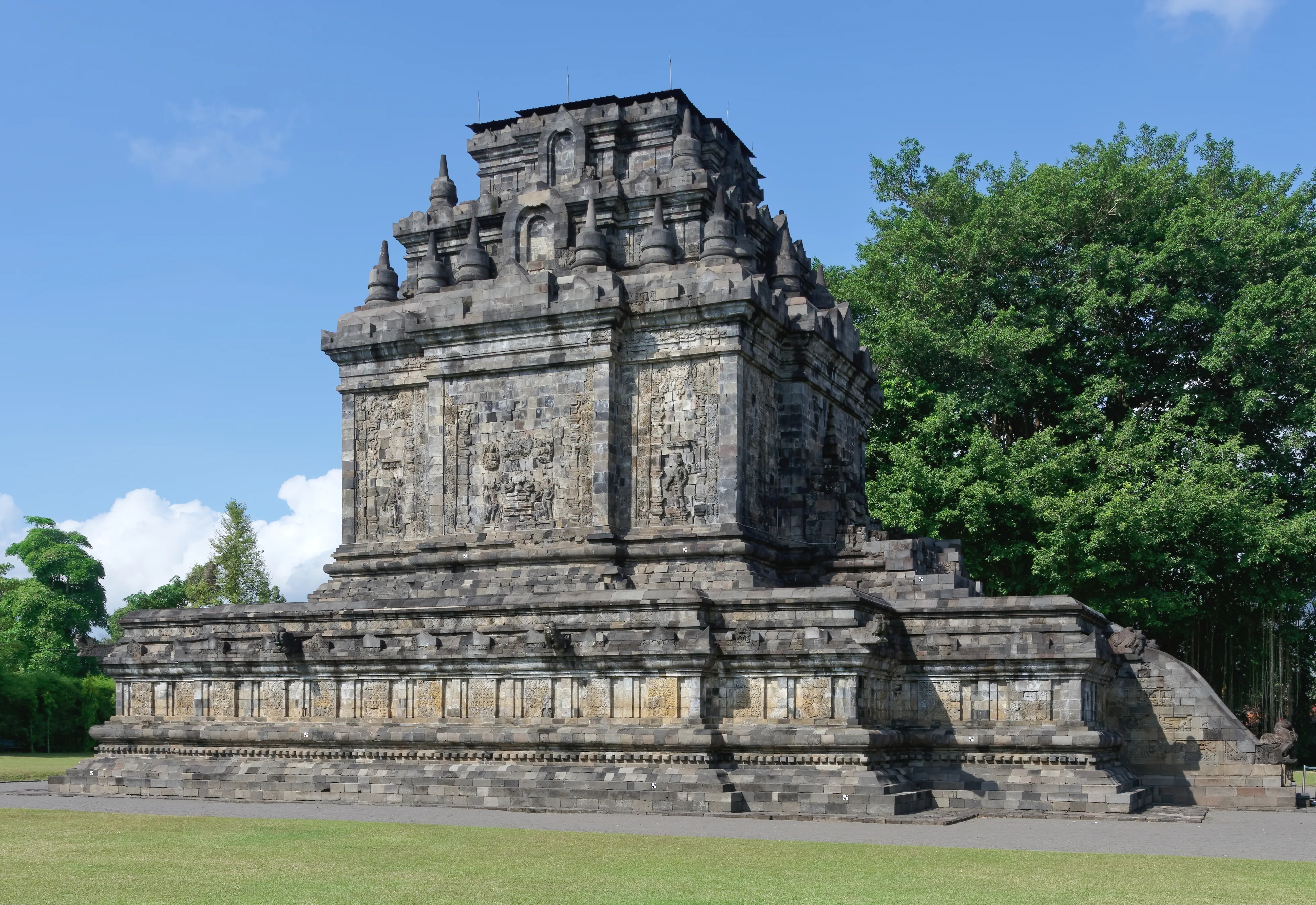 Mendut Temple in Central Java surrounded by trees under a bright sky